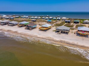 Vue aérienne d’une station balnéaire avec des chalets situés en bord de mer, une plage de sable et l’océan.