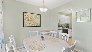 Un espace repas avec une table ronde, des chaises blanches et un luminaire au plafond.