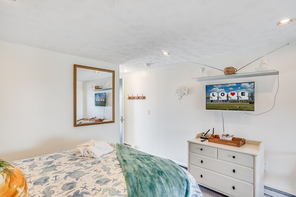 Un dormitorio con una cama, un aparador, un espejo, un televisor y una pared con un letrero que dice 'LOVE'.