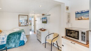 A bedroom with a bed, a desk, a chair, a microwave, and a television. - Bliss on the Bay by Seaside Vacations & Sales (Chincoteague Island)