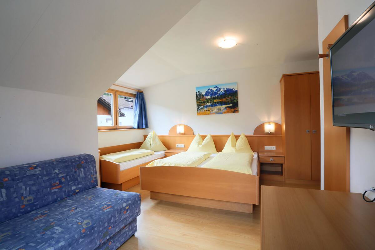Ein Schlafzimmer mit Bett, Sofa, Fernseher und einem Bild an der Wand.