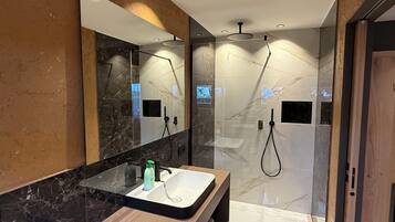 A modern bathroom with a marble vanity, a large mirror, and a glass-enclosed shower area.