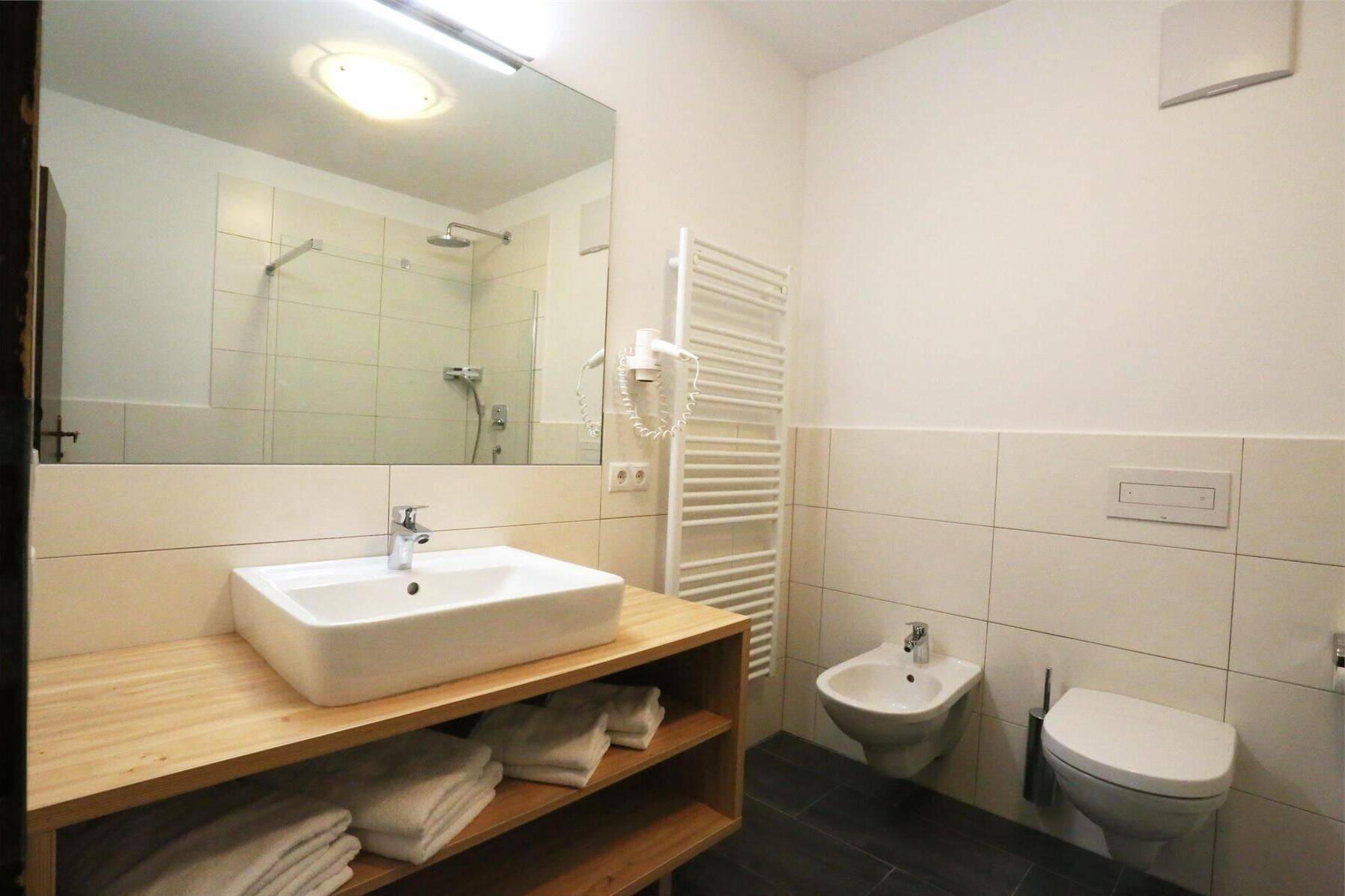 Un baño con un lavamanos blanco, un espejo, una ducha, un bidé y un inodoro.