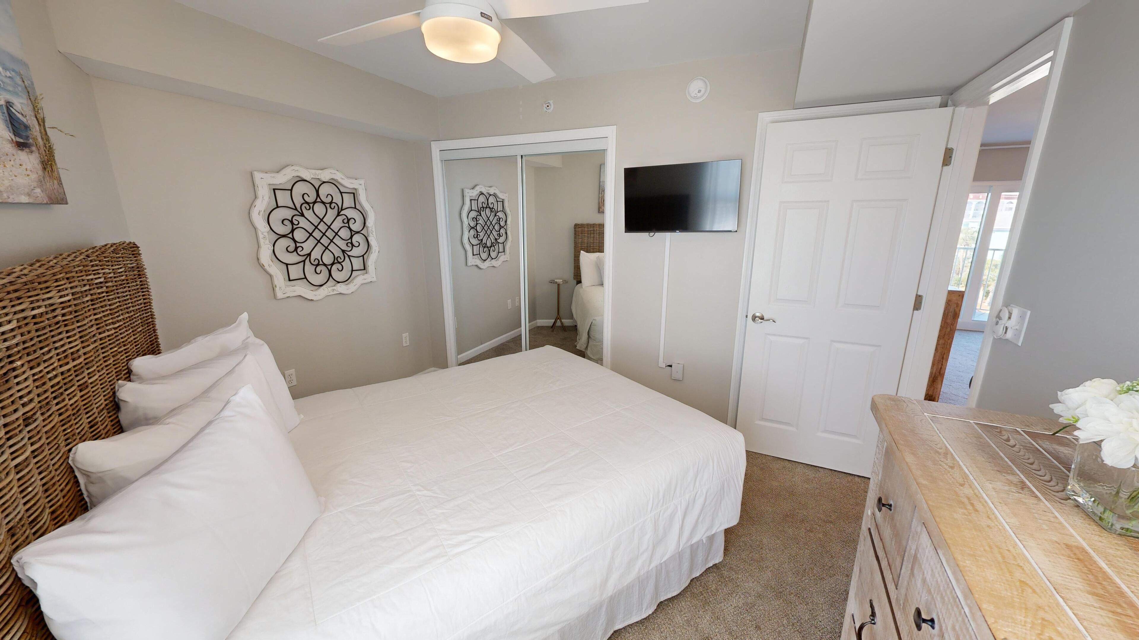 A bedroom with a bed, a dresser, a ceiling fan, and two decorative wall art pieces.