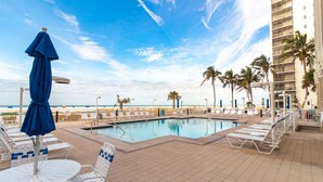 A poolside area with lounge chairs and umbrellas, a clear view of the ocean, and a tiled deck. - Beach Front - Heated Pool- Partial View- 2BR Gullwing #203 (Fort Myers Beach)