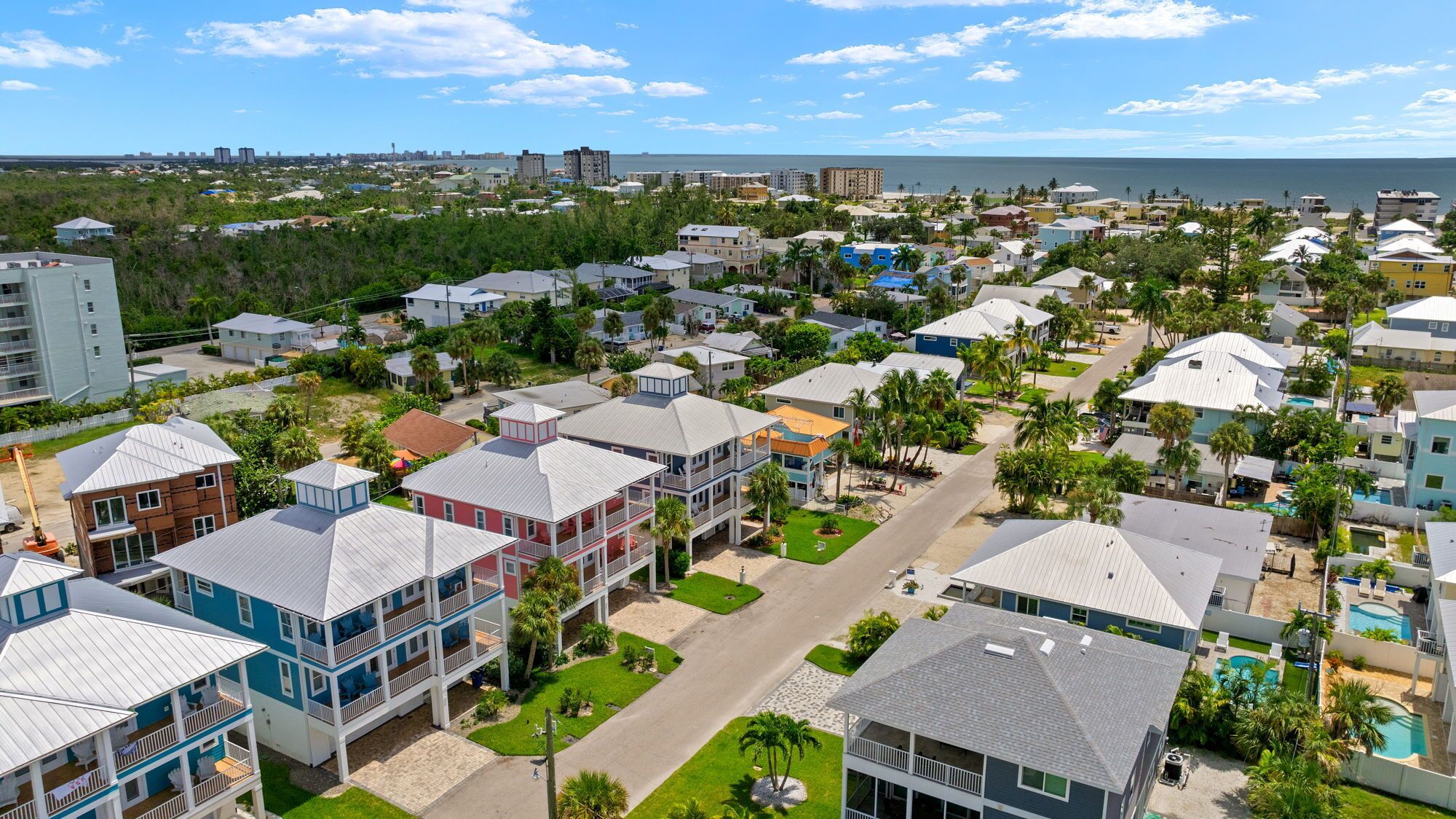 A coastal residential area with houses featuring balconies, a central road, and a view of the ocean.