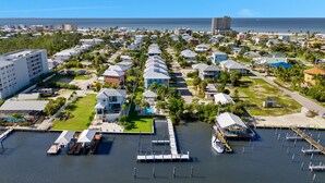 A coastal residential area with houses, a marina, and a large building in the background.