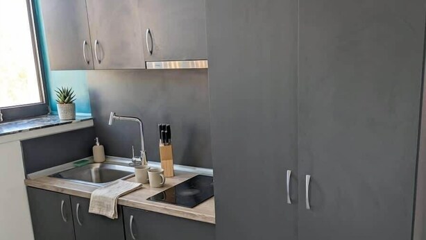 A modern kitchen with grey cabinets, a sink, and a window.