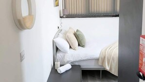 A bedroom with a bed, bedside table, and a window with blinds.