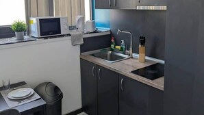A compact kitchen with dark cabinets, a sink, a microwave, and a small dining area with a table and chairs.
