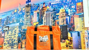 Un sac orange orné des mots « Jenga » et « Jenga GLANT », le tout sur fond de paysage urbain.