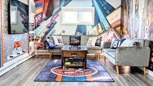 A living room with a large mural of a cityscape, a sofa with a sports jersey, a coffee table, and a rug with a sports logo.