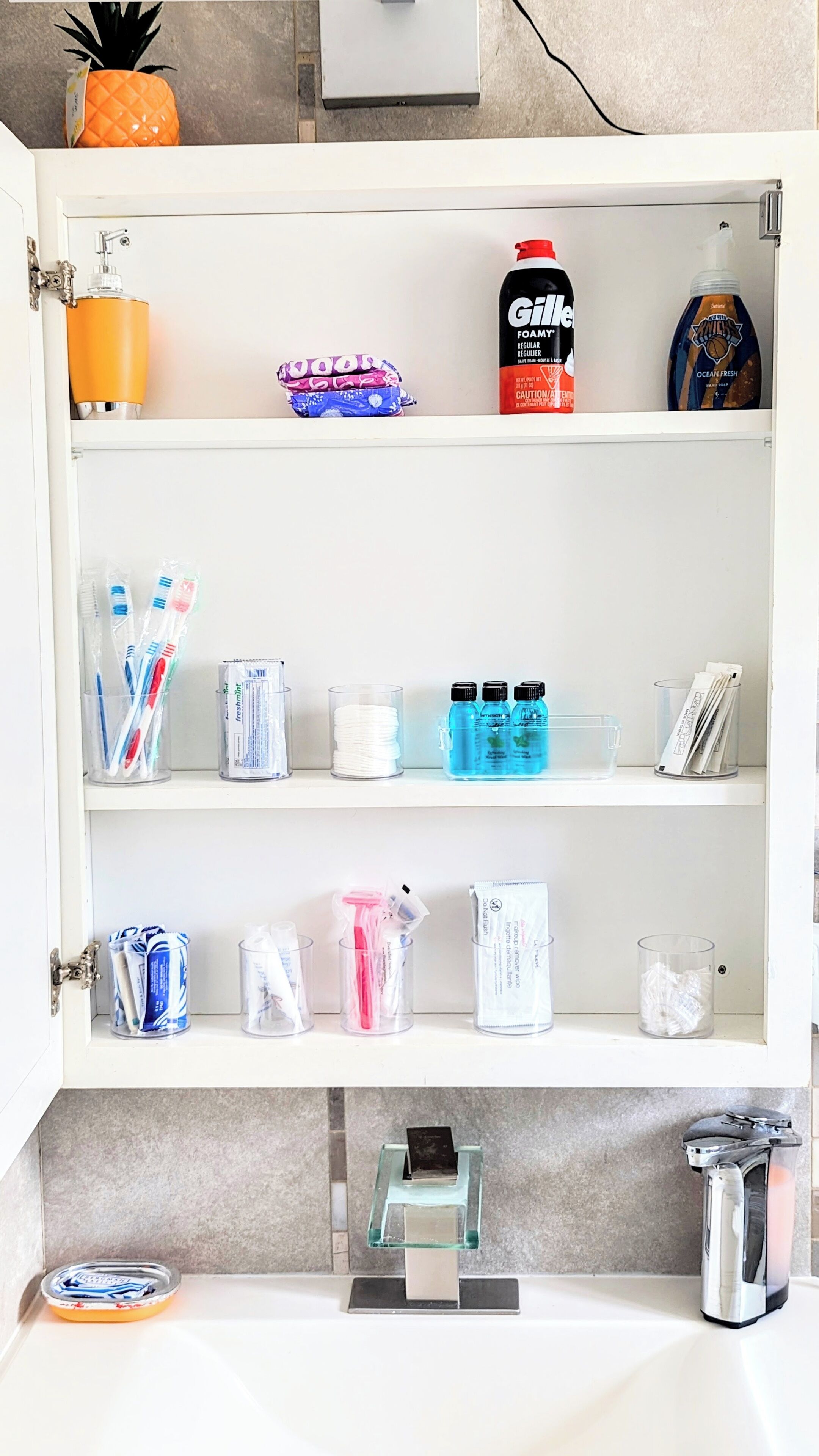 A bathroom with a toilet, sink, and various toiletries organized on shelves.