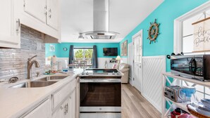 Une cuisine moderne avec des armoires blanches, une hotte de cuisinière en acier inoxydable et un mur d’accent de couleur turquoise.