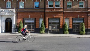 A cyclist riding past a row of brick buildings with storefronts labeled 'Tiffany & Co.' - Sloane Court East VI by onefinestay (London)