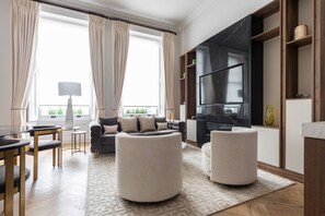 Una sala de estar moderna con sofá, reposapiés y televisor.
