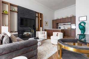 A modern living room with a fireplace, a television, and a dining area with a round table.