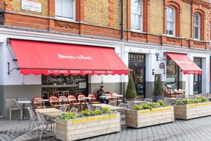 An outdoor seating area with tables and chairs, a red awning, and a sign for 'Brown & Rosie' cafe.