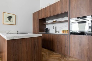 A modern kitchen with wooden cabinetry, a marble countertop, and a built-in oven.