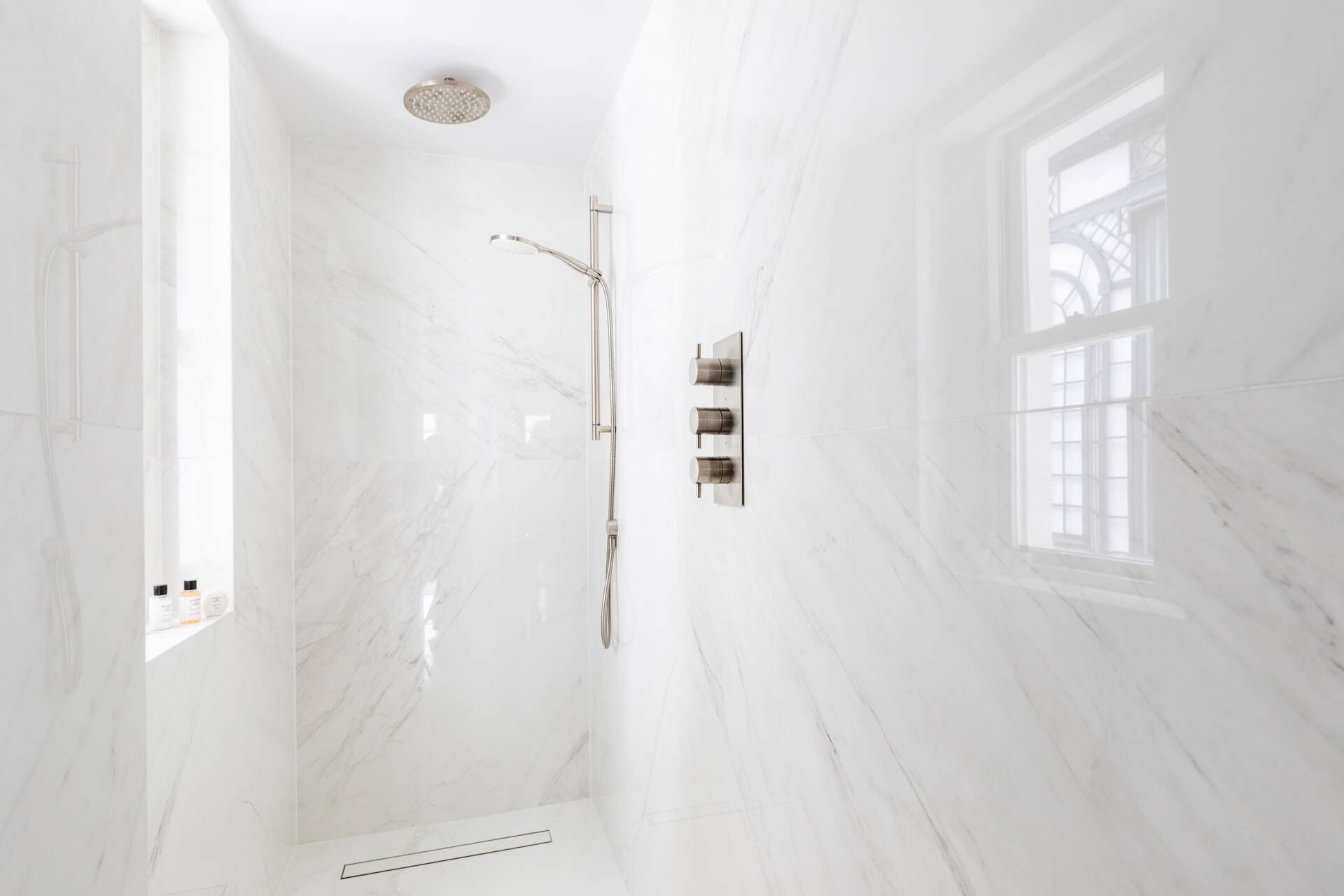 Un bagno con doccia, una finestra e un pavimento in marmo.