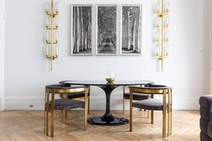 A dining area with a round table, two chairs, and a wine glass.