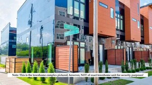 A modern townhome complex with a mix of reflective and wooden facades, multiple entry points, and a well-maintained garden area. - Modern Group Oasis w/ Private Rooftop Deck, Steps to FedExForum (Memphis)