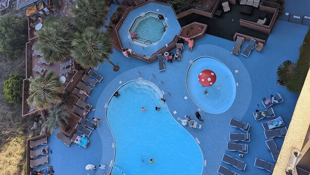 Vue aérienne d’un complexe hôtelier doté de plusieurs piscines, d’espaces de détente et de palmiers.