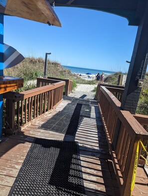 Un paseo marítimo de madera que conduce a una playa con vista despejada al océano.