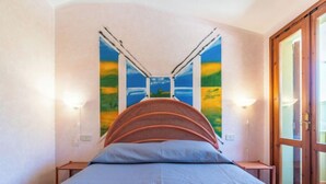 A bedroom with a bed, two wall-mounted lamps, and a door with glass panels. - Vacation home Luli by Interhome (Villasimius)