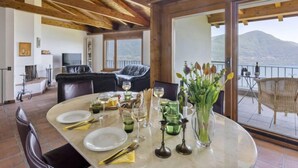 Un comedor con techo de madera, un ventanal con vistas a la montaña y una mesa dispuesta para una comida.
