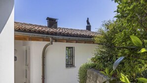 Un estrecho sendero de piedra que conduce a un edificio blanco con techo de tejas y una ventana pequeña.