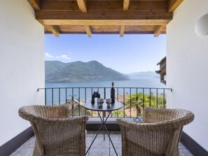 A balcony with wicker chairs and a table, overlooking a lake and mountains. - Vacation home Porta by Interhome (Brissago)
