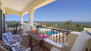 A balcony with a pool, white cushioned chairs, and a table with drinks. - Vacation home Vista by Interhome (São Bartolomeu de Messines)