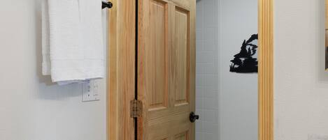 A wooden door with a towel rack and a piano in a bathroom.