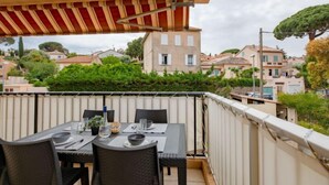 Un balcón con mesa lista para comer, con vistas a una zona residencial con casas y vegetación.