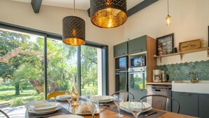 Un comedor con una mesa dispuesta para cuatro personas, una cocina con electrodomésticos modernos y vistas al exterior.