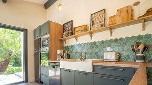 Una cocina moderna con armarios oscuros, encimera de madera y salpicadero con azulejos verdes.