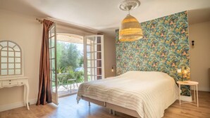 Un dormitorio con una cama grande, una ventana con cortinas, un escritorio y una pared con diseño.