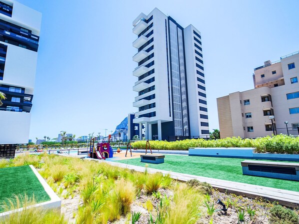 A modern urban landscape with high-rise buildings, a playground, and landscaped areas.