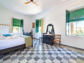 Une chambre à coucher avec un lit, une commode, une chaise et un ventilateur de plafond.