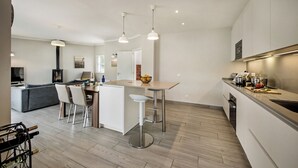 A modern kitchen with a central island, bar stools, and pendant lighting. - Beautiful detached Villa, 10 minutes walk from Porto Do Mos beach (Lagos)