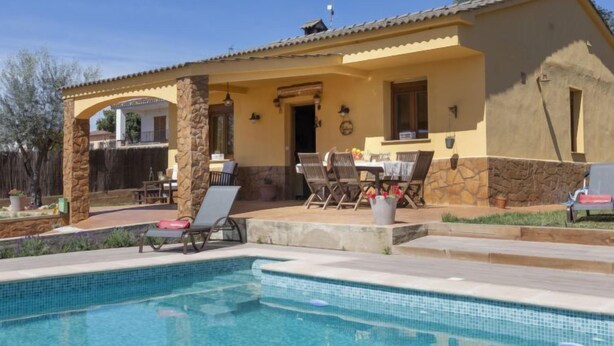 A poolside area with a covered patio, outdoor seating, and a stone pillar. - Ca La Lou by Interhome (Sils)