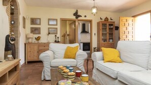 A cozy living room with two white sofas, a wooden coffee table with pastries, and a fireplace in the background. - Ca La Lou by Interhome (Sils)