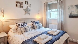 Un dormitori ben organitzat amb un llit, taules de nit i una decoració d'estels a la paret.