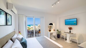 Une chambre d’hôtel avec un lit, un bureau, une chaise, une télévision et une vue sur la mer.