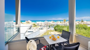 A balcony with a table set for breakfast, overlooking a coastal cityscape. - Creta Sun, Studio 104 Sea view (Rethymno)