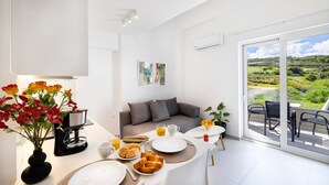 Una sala de estar moderna con sofá, mesa de centro y comedor con platos, tazas y flores.
