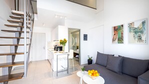 Un espacio de estar moderno con una escalera, una zona de comedor y un sofá.