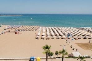 A beach with rows of umbrellas and sun loungers, a clear sky, and calm sea. - Creta Sun, Mezzanine 203 Sea view (Rethymno)
