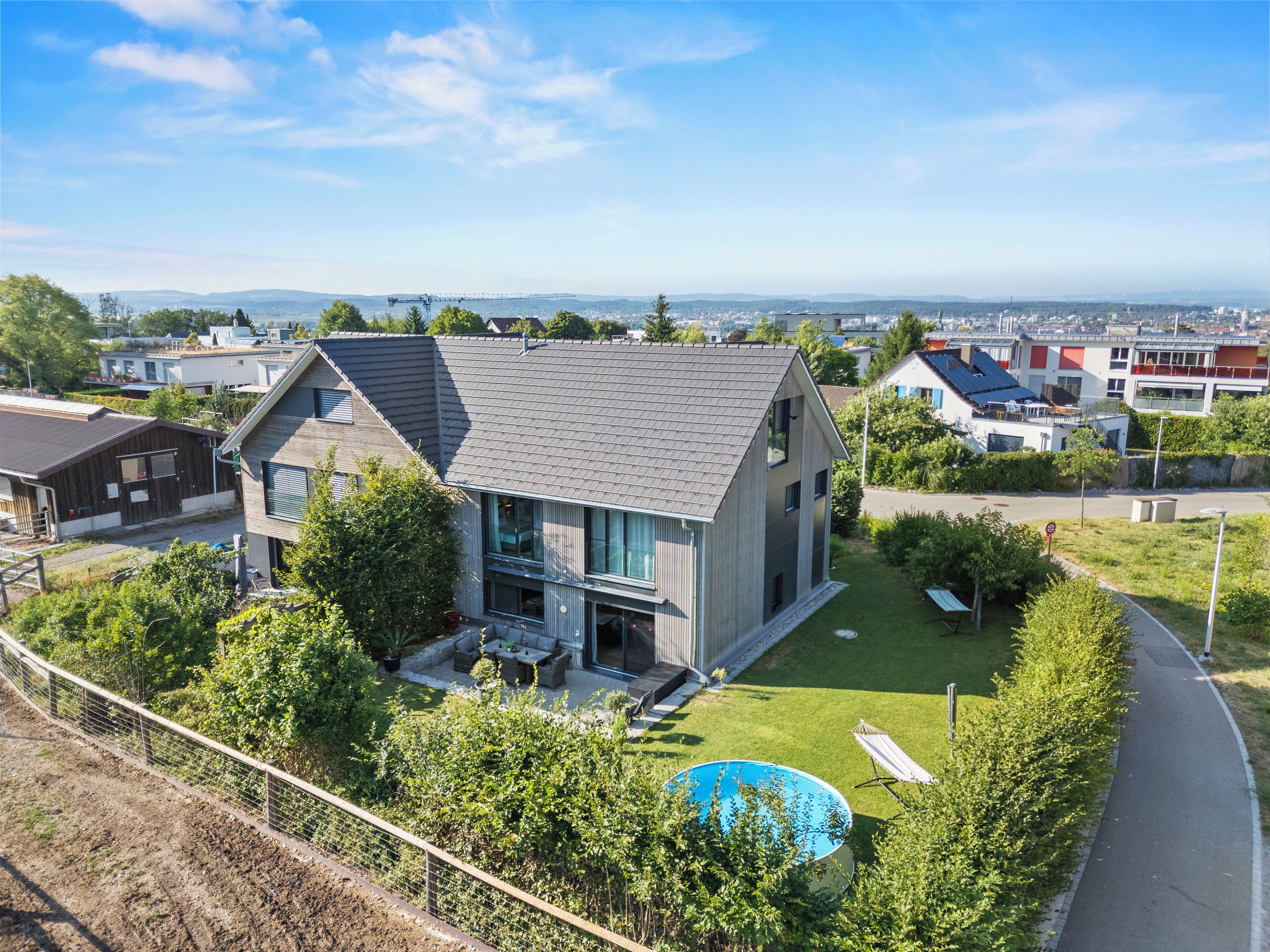 Une maison moderne dotée d’une grande baie vitrée, d’une piscine et d’une pelouse bien entretenue.